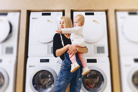 母亲与婴孩在洗衣机的背景下