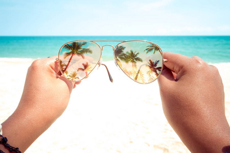 夏季年轻的棕褐色女子手捧太阳镜在夏季的热带海滩上放松和休闲。复古调