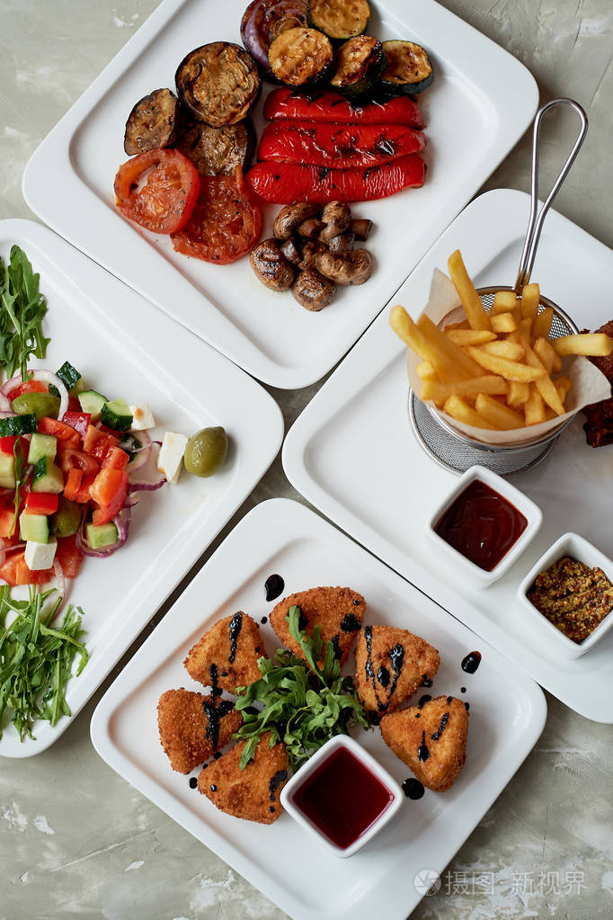 餐厅里的桌子不错丰盛可口的午餐包括奶酪乳酪在面糊希腊沙拉和烤蔬菜