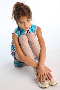 穿着亚洲蓝色连衣裙的漂亮女孩正坐在白色的背景上.