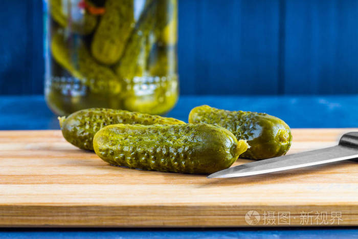 黄瓜或用小刀在木菜板上腌的黄瓜蓝色的灰色背景银行与黄瓜