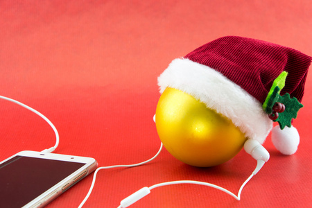 圣诞球以圣诞老人的帽子和带着耳机上红色与副本空间, 智能手机