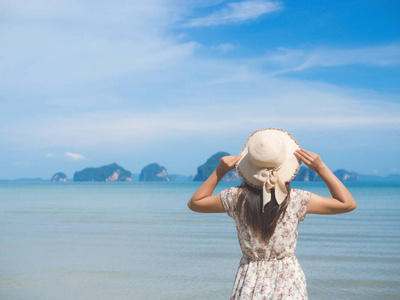 在暑假里戴着草帽和看看海洋沙滩裙的女人