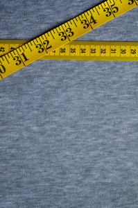 黄颜色的数值指标形式厘米或英寸皮尺位于针织坯布。具体的身体尺寸的缝制衣服的背景概念