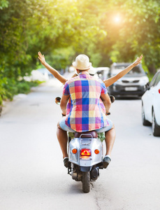 快乐的年轻夫妇骑在街头背着老式踏板车