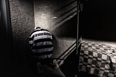 囚犯坐在小监狱牢房的角落照片