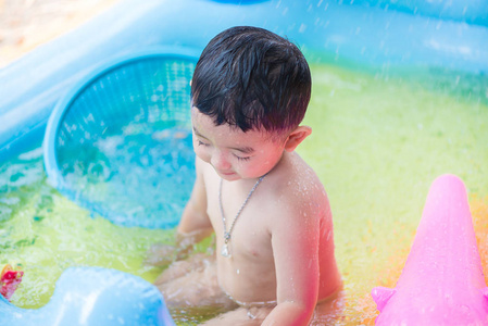 在炎热的夏天在充气婴儿游泳池玩耍的亚洲孩子