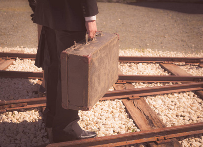 年轻夫妇与老式手提箱走在 trainlines