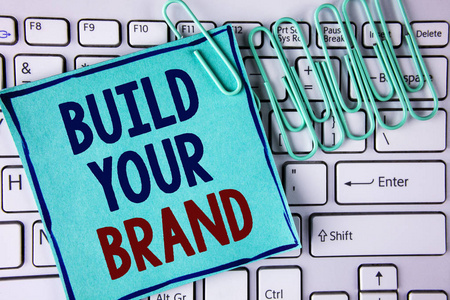 字写文字打造你的品牌。企业理念创建您自己的徽标口号模型广告电子营销写在贴在白色键盘纸针旁边的粘纸条纸上