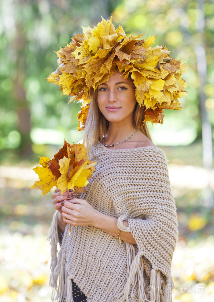 女孩秋天。年轻的女孩，一个花圈上他们的脑袋和枫树的叶子叶子在手中