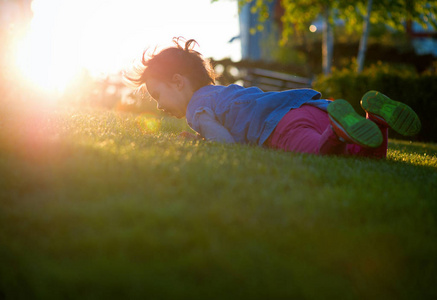 小女孩玩在操场上用白色模糊公园背景在日落时分