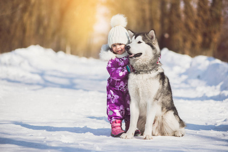 小女孩与美丽的大狗在森林在冬天时间