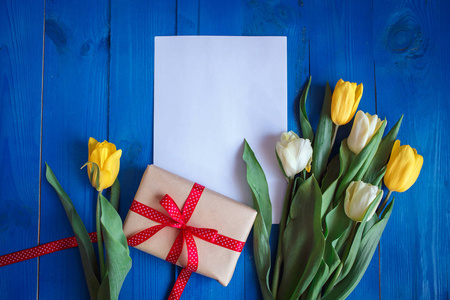 春季郁金香花 礼品盒 纸卡从上面平躺风格的蓝色木制的桌子上
