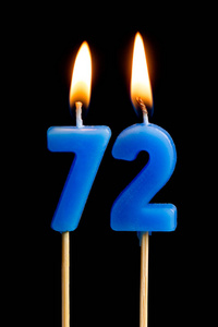 燃烧蜡烛的形式为72七十二 数字, 日期 的蛋糕孤立的黑色背景。庆祝生日周年纪念日重要日期节日餐桌设置的概念