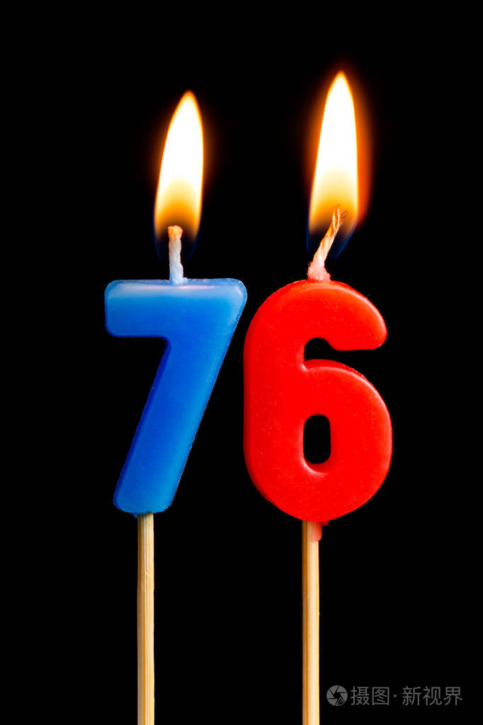 燃烧蜡烛的形式为76七十六数字日期的蛋糕孤立的黑色