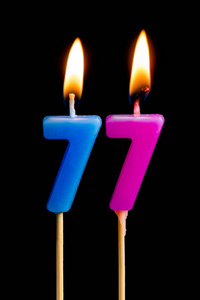 重要日期燃烧蜡烛的形式为77七十七 (数字, 日期) 的蛋糕孤立的黑色