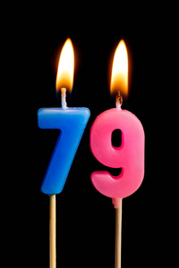燃烧蜡烛的形式为79七十九 (数字, 日期) 的蛋糕孤立的黑色背景.
