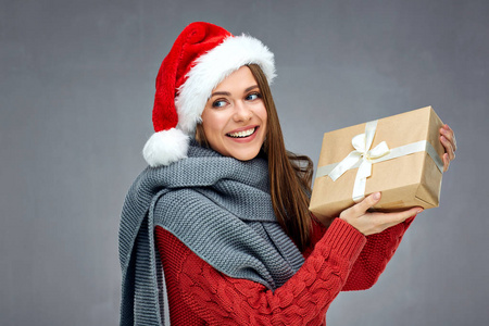 微笑的女人戴着圣诞帽拿着纸礼盒, 一边看着灰色的墙壁背景
