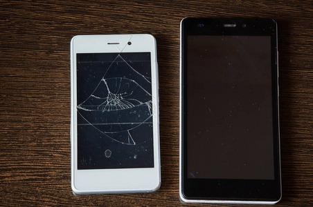 裂缝的智能手机屏幕智能手机, 在木桌上的屏幕被打破照片