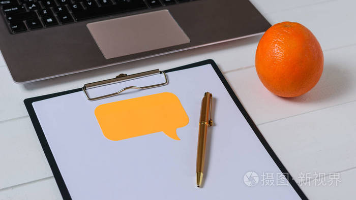 用纸膝上型电脑和橙色放在平板上的文字放在白桌上