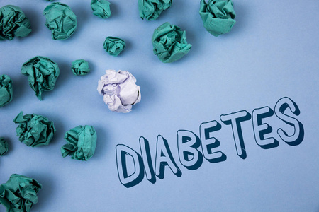 手写文字书写糖尿病。概念意味医学病症被诊断以增加的高水平糖写在蓝色背景皱巴巴的纸球旁边