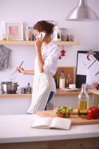 电话在家里的厨房里一个微笑的女人的肖像