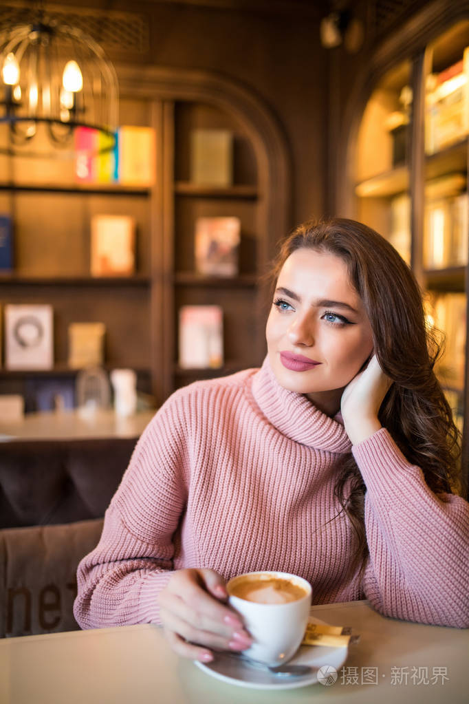 年轻漂亮的女人在咖啡馆里喝咖啡