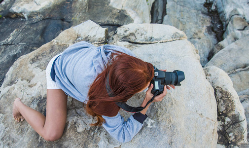 红发女摄影师正在拍摄山背景照片