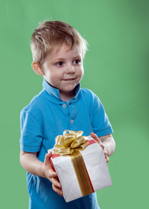 一个小男孩手持绿色背景上他手中的礼品盒