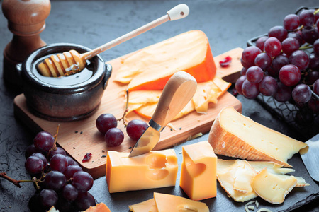 黑色石板板与各种奶酪, 装饰葡萄, 面包和蜂蜜