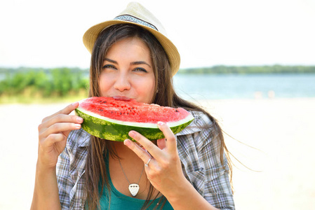 快乐的年轻女人在沙滩上吃西瓜。青年 lifestyl