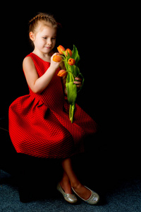 一个黑色背景的郁金香花束的小女孩