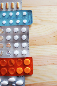 片剂药片在水泡包装在自然木头背景.药学,医药和健康理念.