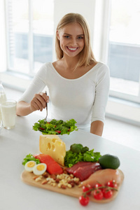 女人吃鸡蛋健康的女人在厨房里,餐桌上的食品吃沙拉照片