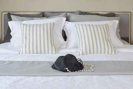 现代卧室条纹的枕头，在床上的黑帽子
