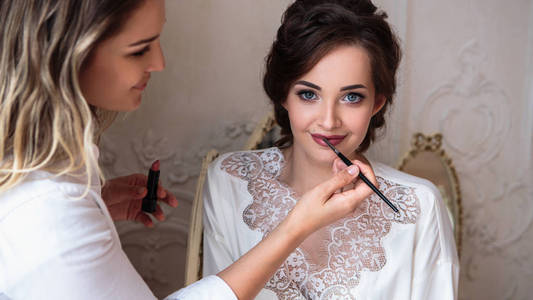 化妆师准备美丽的新娘在婚礼前的早晨