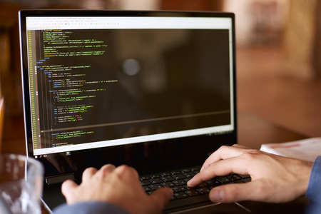 程序员代码后视图在开发者程序员的肩膀拍摄与笔记本电脑.