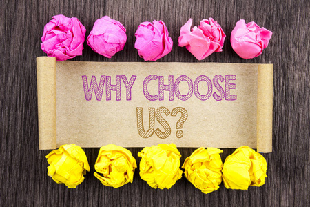 编写文本为什么选择我们的问题。概念意义的选择客户满意度的原因在纸上写有折叠纸张的黄色和粉红色的木质背景