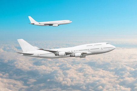 两架大型的白色客机在云层上空平行飞行