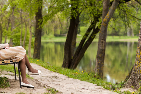 美丽的年轻女子坐在公园长椅上的脚