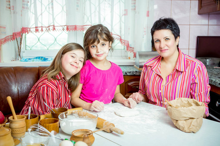 妈妈教她的两个女儿在厨房做饭