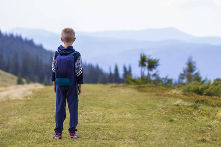 小男孩带着背包徒步旅行, 在风景秀丽的夏日绿山山上。儿童独享山水山景。积极的生活方式, 冒险和周末活动的概念