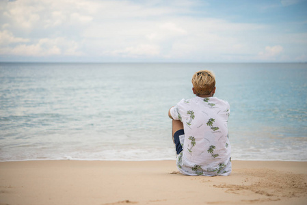 年轻的时髦男子放松坐在海边