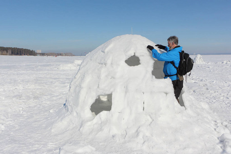 冬天在下雪的水库上建造一座冰屋的人