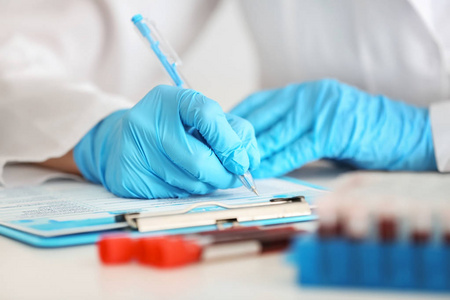 实验室工人填写表在试验管附近与血液样品在桌上