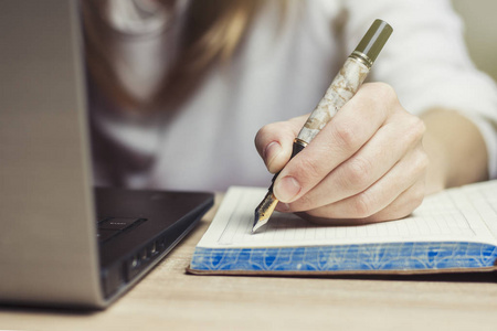 钢笔在女性手做笔记在日志。工作环境保护