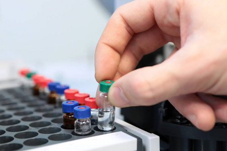 人们手握试管瓶设置为在气液相色谱仪分析。在色谱瓶插入实验室玻璃瓶的实验室助理