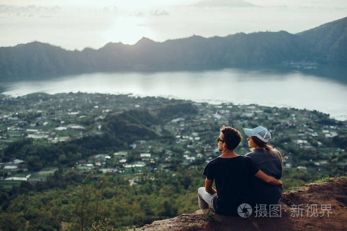 情侣坐在悬崖上的男人和女人轻松的山和云鸟瞰爱情和旅行的快乐情绪