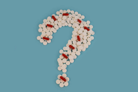 医学问题是白色药丸和红色胶囊的问号在蓝色背景下