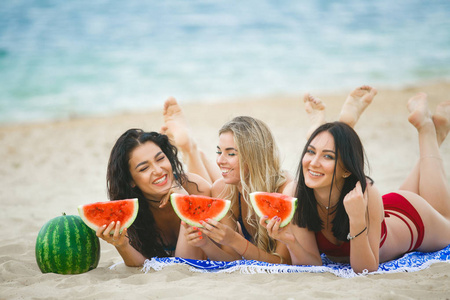 在海滩上吃西瓜和享受阳光的女朋友